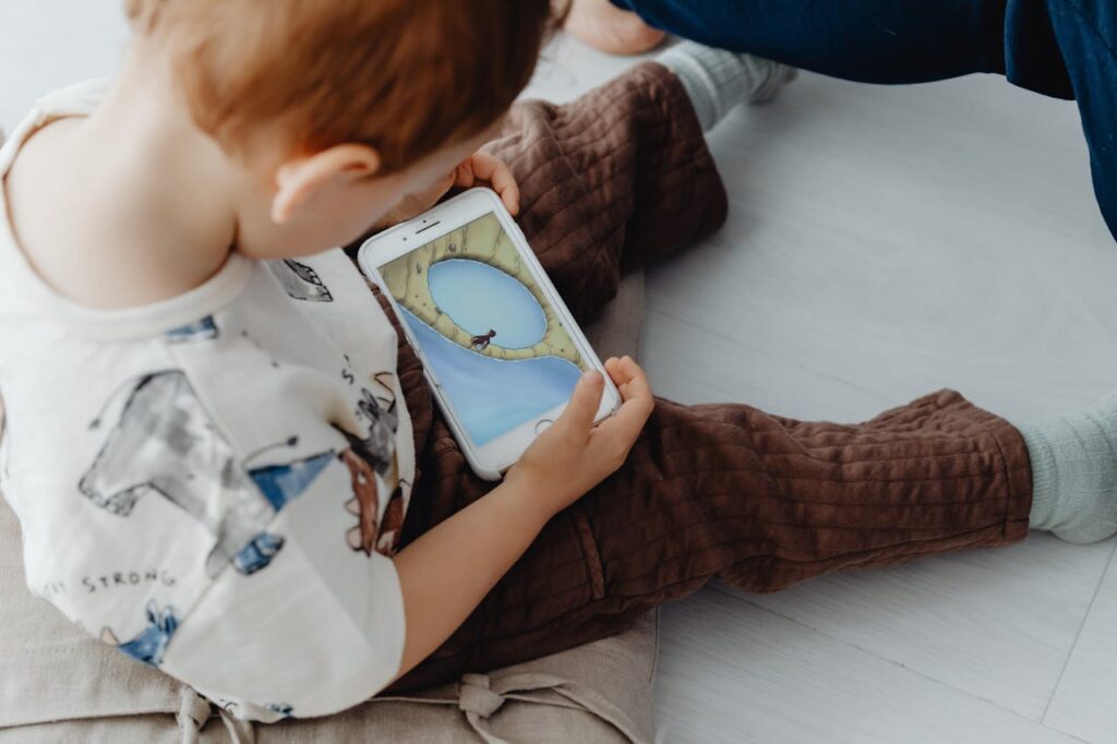 A young child playing an educational game on a smartphone indoors, focused on learning.